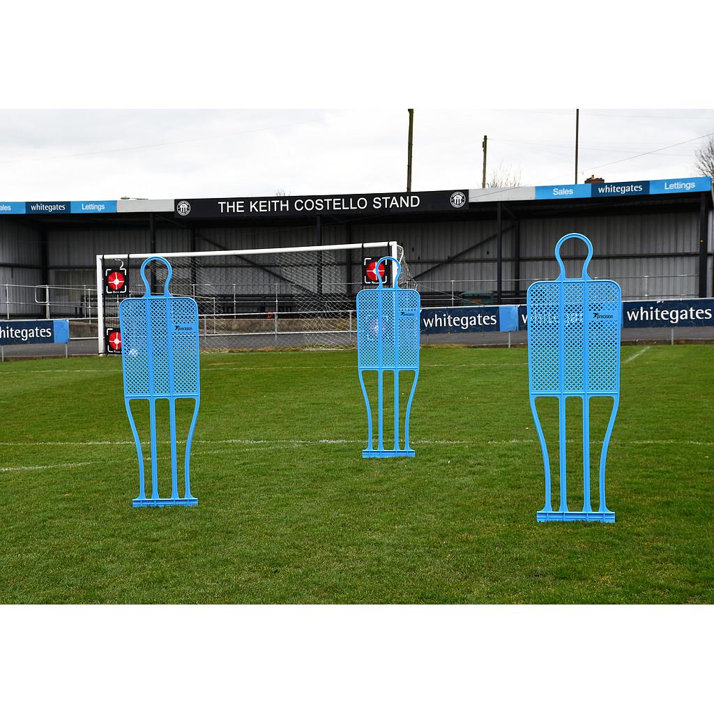 Three Precision Training Precision Pro Club Mannequins (Single), blue in color, are set up on a soccer field in front of The Keith Costello Stand—perfect for tactical drills and free kick practice—with ads and fencing visible behind.