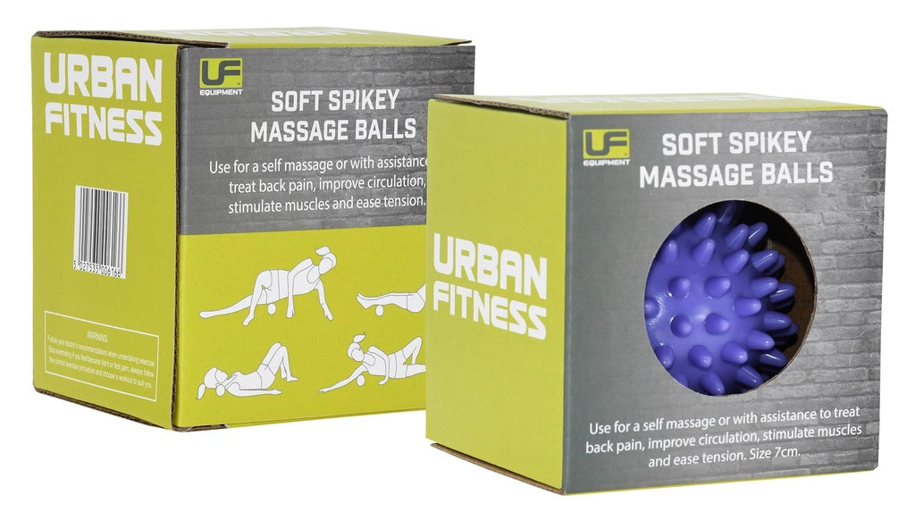 Two green Urban Fitness boxes contain Urban Fitness Soft Spikey Massage Balls for improving circulation. One shows a purple spiked ball; both packages illustrate people using the ball on the floor for back pain relief.