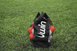 A Uwin Small Ball Carry Bag, featuring black mesh and the Uwin logo in white, holds red and white balls and is placed on green grass.