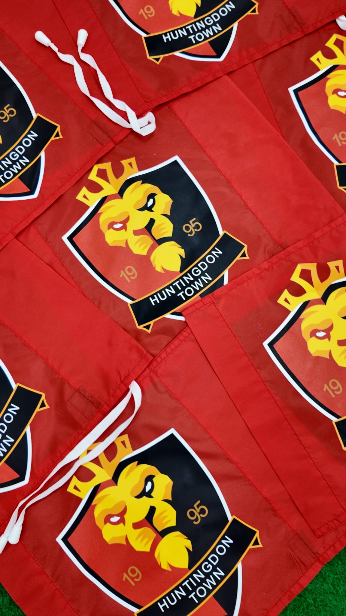 Custom Printed Corner Post Flags (Single Colour Flag & Logo) by Martin Berrill Sports are displayed on green grass, some overlapping, showing how these stylish personalised flags add distinction to any event or match day.