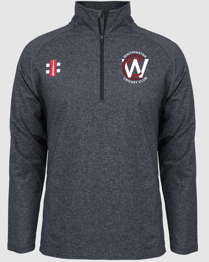 The Gray Nicolls Whitminster CC Velocity Mid Layer is a dark grey, long-sleeve quarter-zip pullover with moisture control, stretch fit, stand-up collar, club name and W logo on the left chest, and a red-white emblem on the right.