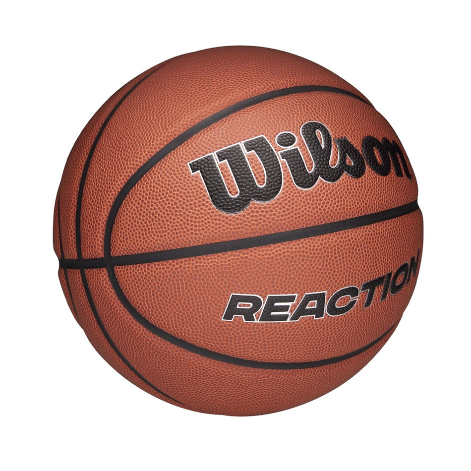 The Wilson Reaction Plus Basketball, featuring brown composite cover with black lines and "REACTION" printed on it, delivers durable performance for both indoor and outdoor play. Shown on a white background.