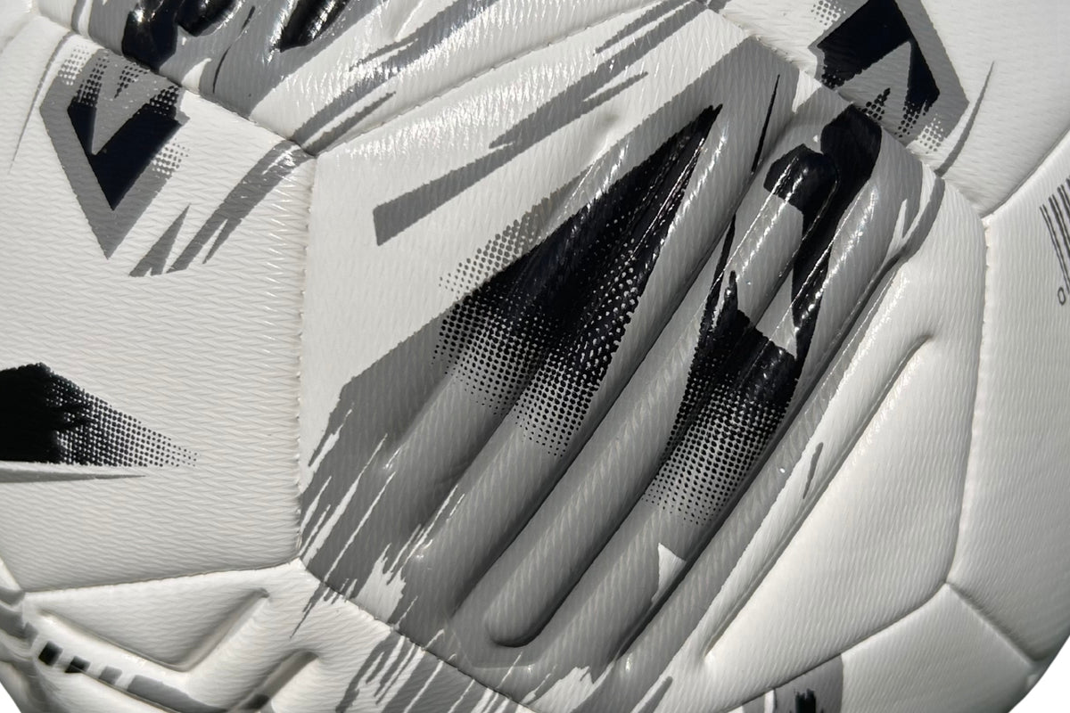 Close-up of the Samba Infiniti Max Training Ball by Samba Sports—a white football featuring a textured surface with black and gray geometric patterns. The detailed image showcases its stitching, precision-moulded grooves, and distinctive design elements, making it an ideal choice for your collection of training footballs.