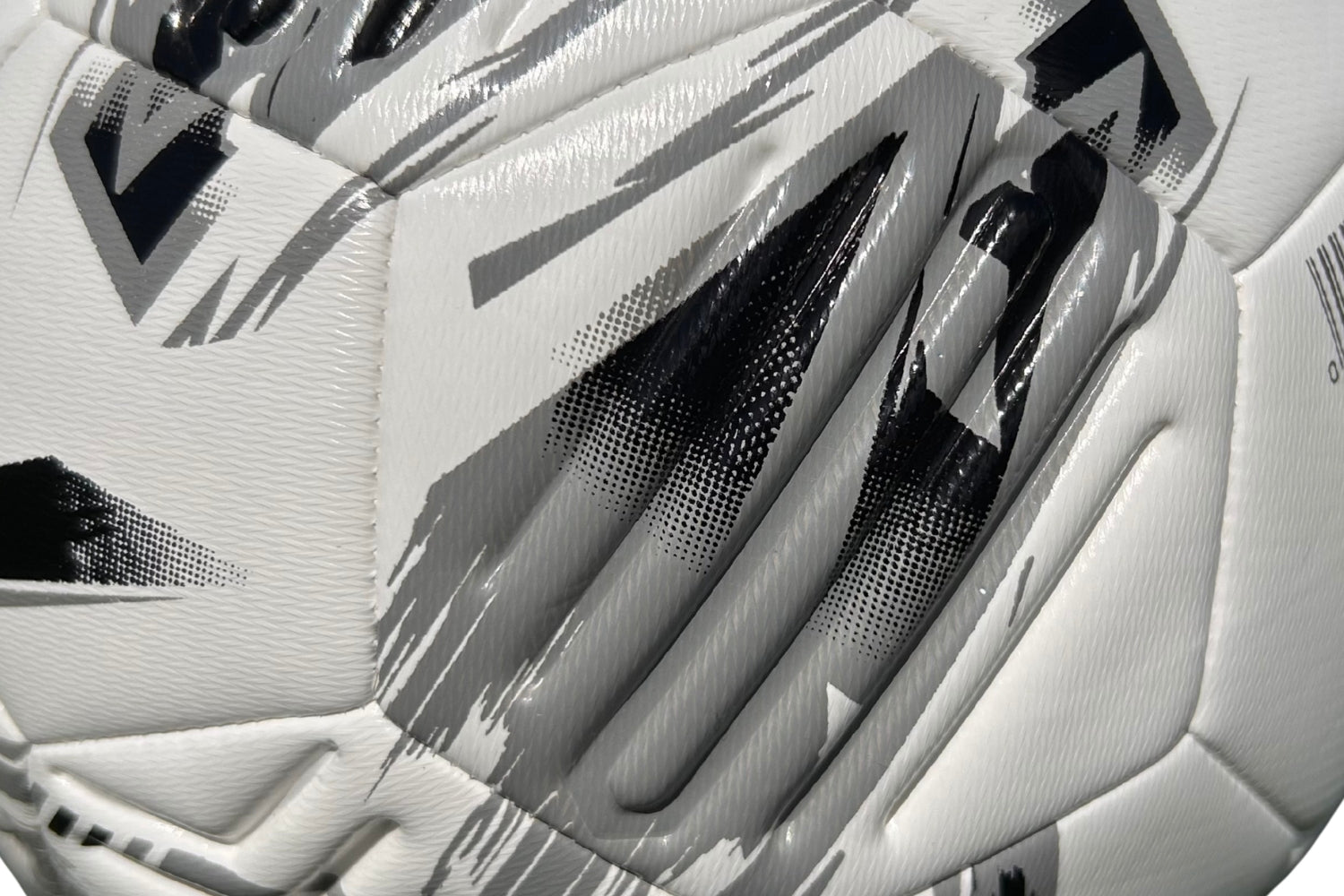 Close-up of the Samba Infiniti Max Training Ball by Samba Sports—a white football featuring a textured surface with black and gray geometric patterns. The detailed image showcases its stitching, precision-moulded grooves, and distinctive design elements, making it an ideal choice for your collection of training footballs.