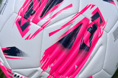 Close-up of the Samba Infiniti Max Training Ball by Samba Sports—a white football showcasing bold pink and dark blue graphic patterns with textured panels and precision-moulded grooves for enhanced control, making it ideal for training sessions.