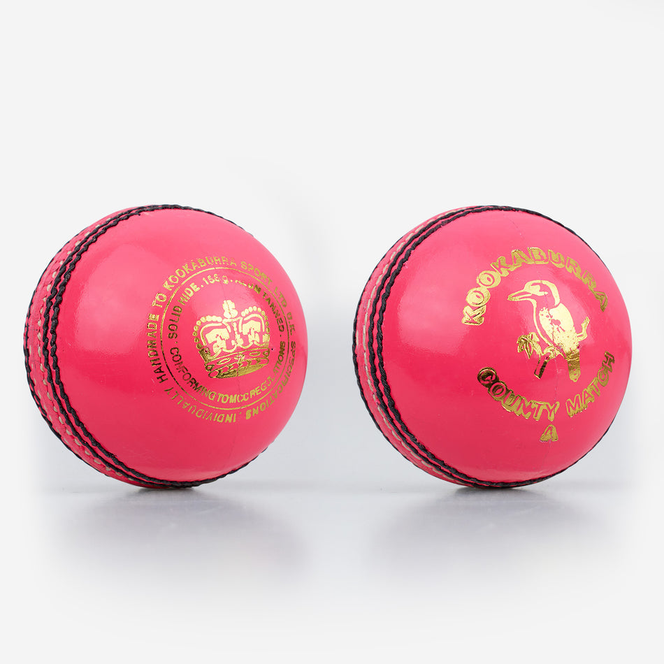 Two pink Kookaburra County Match Cricket Balls with black stitching and gold logos are shown side by side on a white background.
