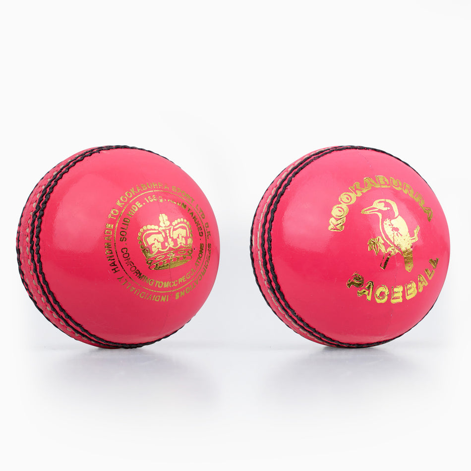Two bright pink Kookaburra Pace Cricket Balls with black stitching and durable hide covers—one features a gold crown logo, the other shows the Kookaburra bird logo and "Kookaburra Pace Cricket Ball" text in gold.