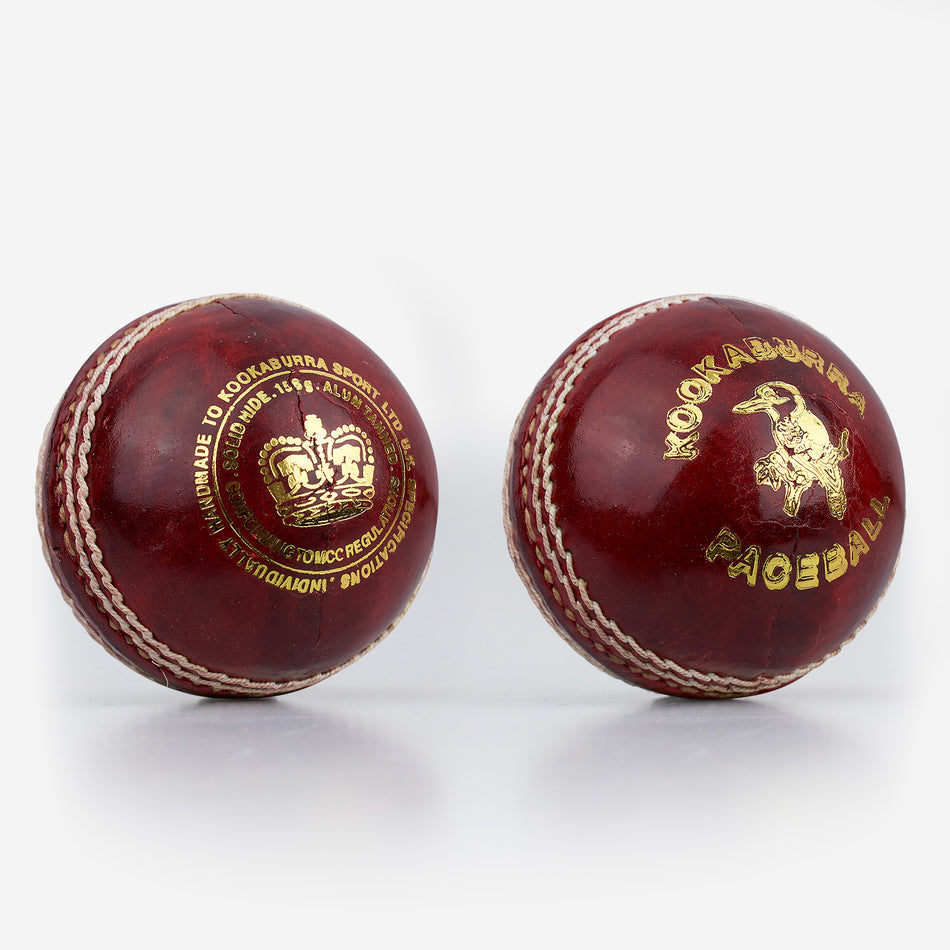 Two red Kookaburra Pace Cricket Balls by Kookaburra, with white stitching and gold branding, are displayed side by side on a plain white background. Each is hand sewn with a durable hide cover.