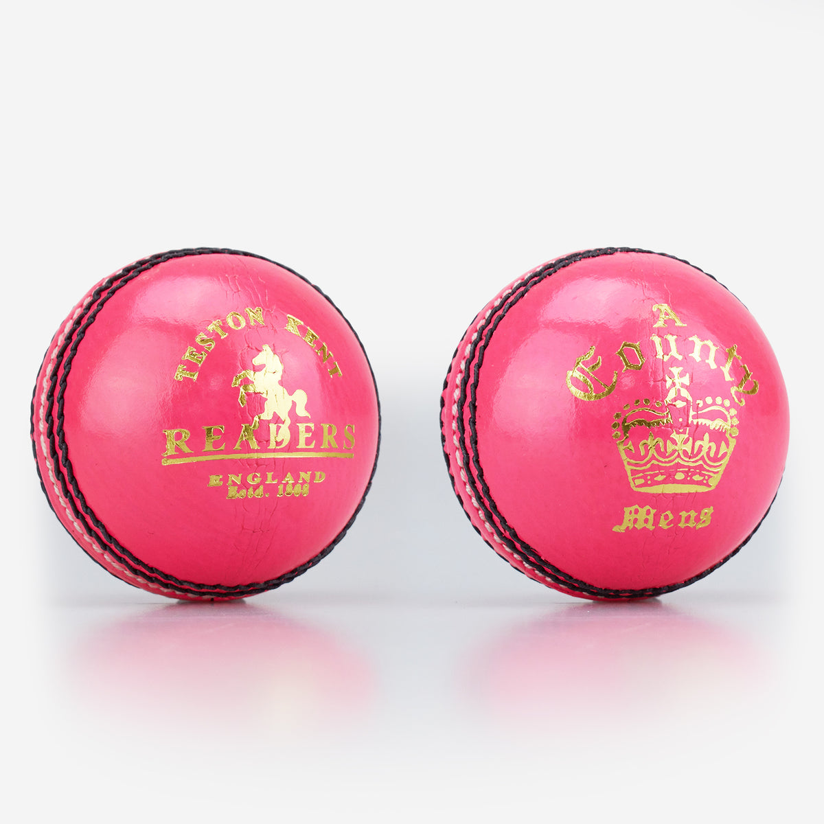 Two pink Readers County Crown Coloured Cricket Balls with black stitching and shiny leather surfaces, ideal for training or evening matches, are set on a white background. Each features distinctive gold branding: the Readers logo and a crown.