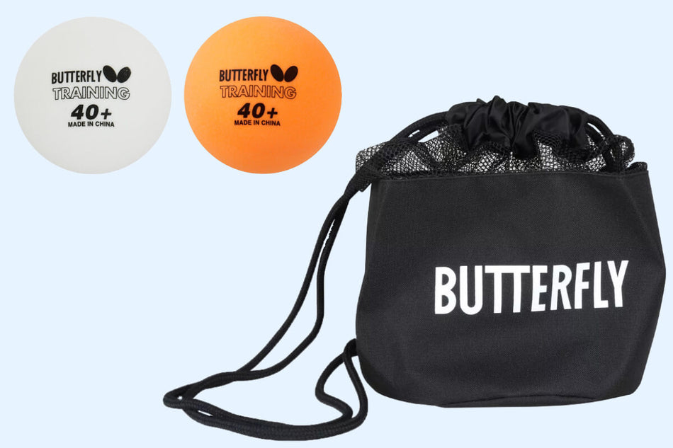 Two Butterfly 100 Training Balls, one white and one orange, are placed next to a black carry bag with “Butterfly” printed in white letters.