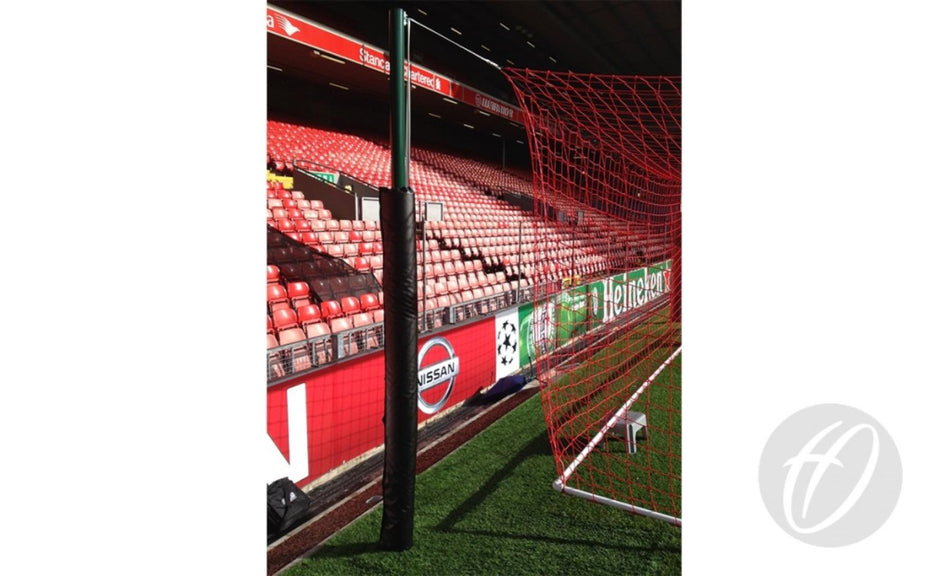 A close-up of a red football goal net with empty red stadium seats and advertisements, including Nissan and Heineken, in the background. The goalposts are protected by Harrod Sport UEFA Net Support Pads 2.1M, featuring 2100mm high foam pads covered in durable black PVC for enhanced safety and style.