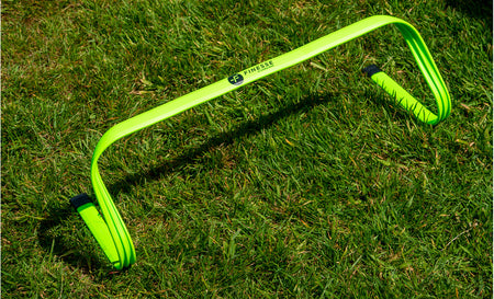 A Finesse Agility Bundle hurdle in bright green, branded by Finesse, sits on the grass—ideal for sports or fitness training sessions as part of an agility kit.