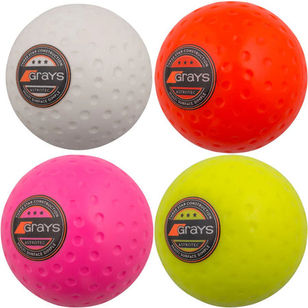 Four Grays Astrotec Hockey Balls in white, orange, pink, and yellow—each with a circular Grays logo—are shown against a plain background. Ideal for club matches at county level.