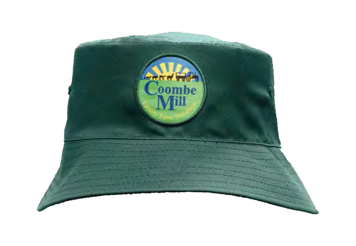 The Martin Berrill Sports Breathable Bucket Hat is a green polyester twill hat with a round embroidered patch featuring a yellow sun, blue sky, and "Coombe Mill" text. This stylish hat can also be customized for a personal touch.