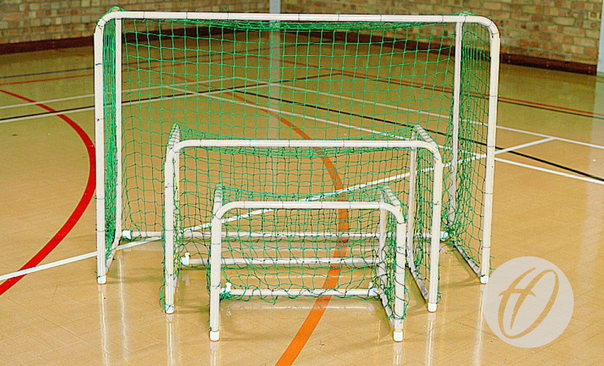 Three Harrod Sport Mini Hoc Goals (1000mm x 1400mm), white and green with folding side frames for easy storage, are nested together on a gym floor featuring brick walls and court lines, ideal for indoor use.
