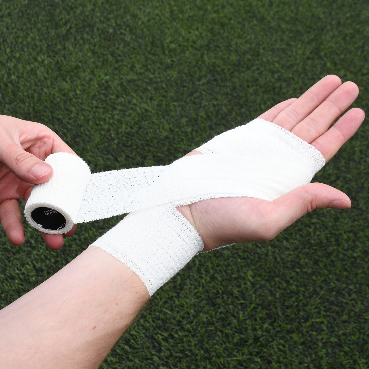 White Precision elasticated adhesive bandage being applied across the palm and wrist