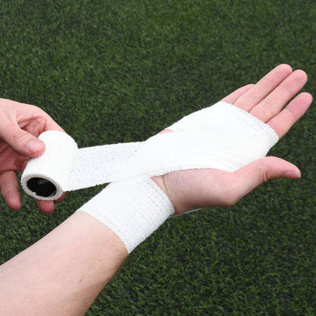 White Precision elasticated adhesive bandage being applied across the palm and wrist