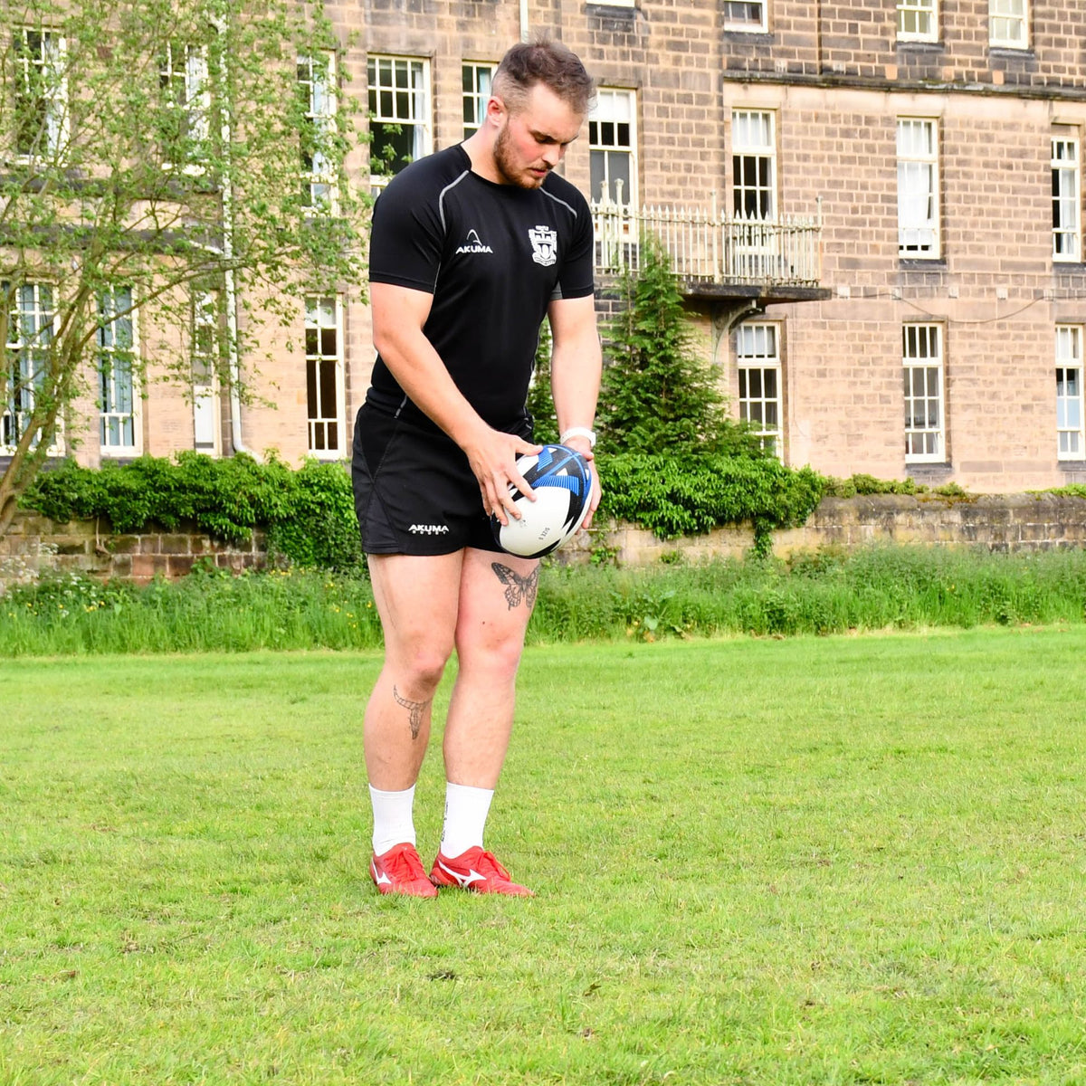 Player standing on a grass pitch preparing to kick the Precision Momentum Rugby Training Ball