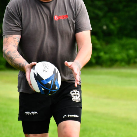 Player in a grey T-shirt holding the Precision Momentum Rugby Training Ball in both hands