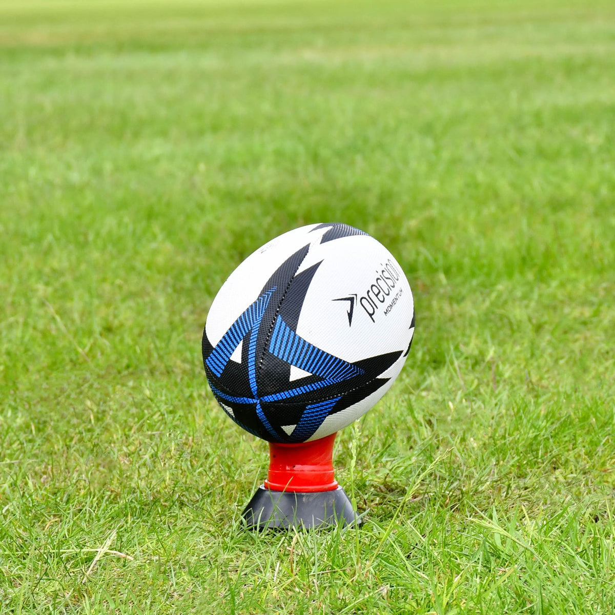 Blue Precision Momentum Rugby Training Ball balanced on a red kicking tee, shown from a distance