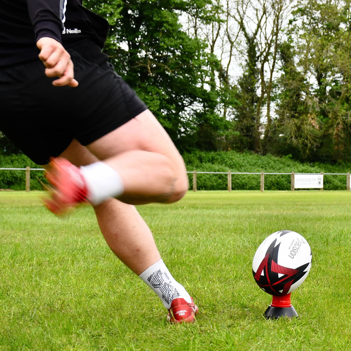 Player kicking the red Precision Momentum Rugby Training Ball off a red tee
