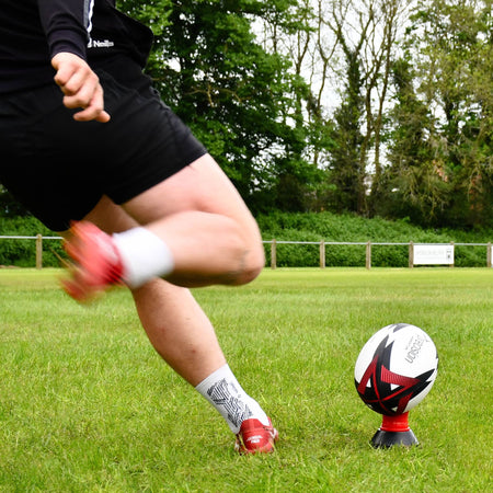 Player kicking the red Precision Momentum Rugby Training Ball off a red tee