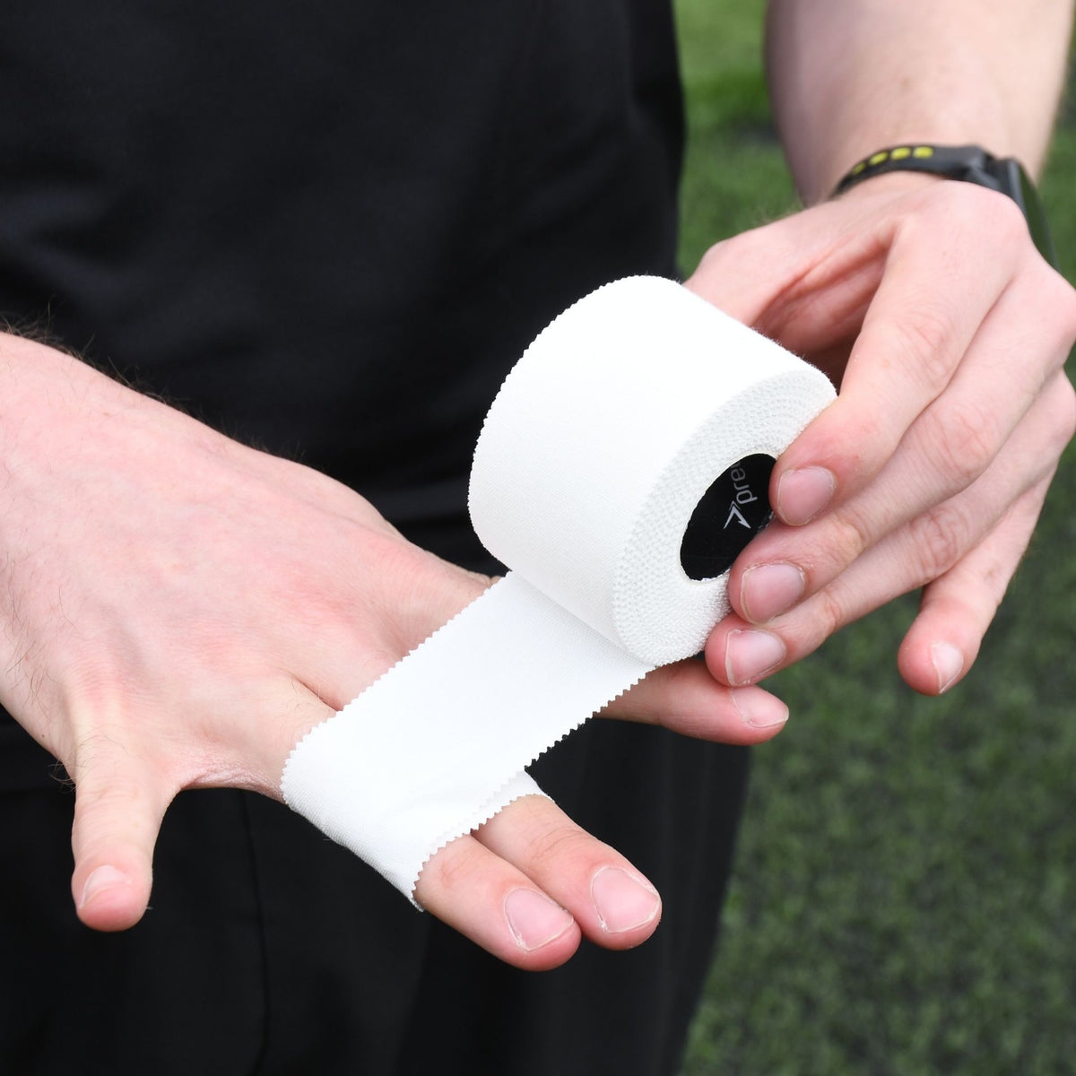 Player wrapping white Precision zinc oxide tape around the hand outdoors