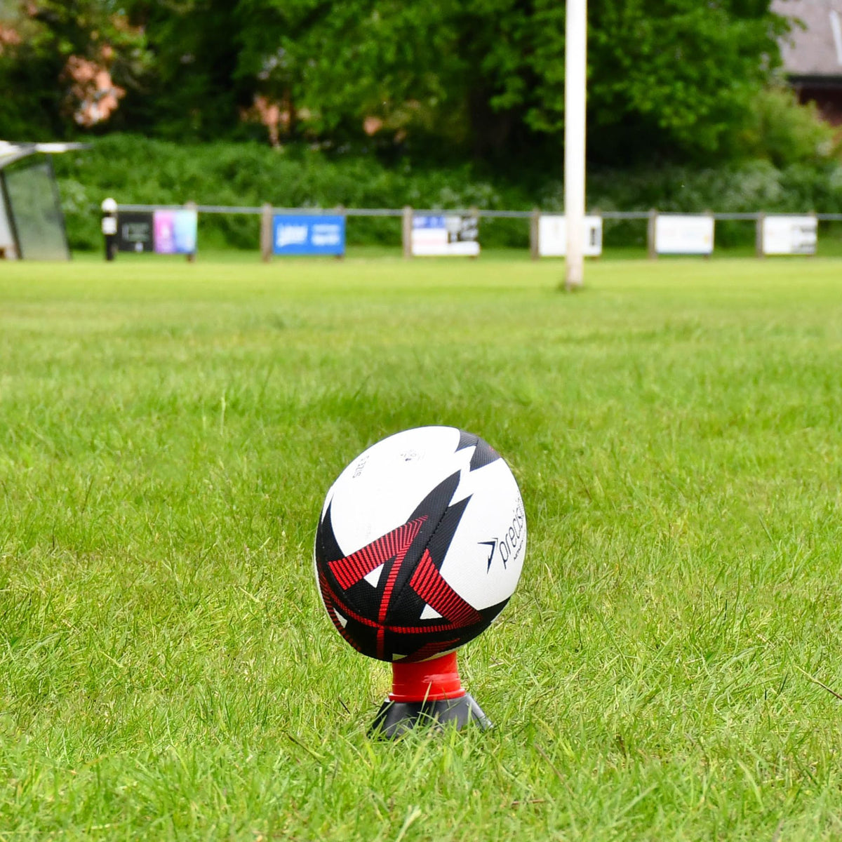 Close-up of the red Precision Momentum Rugby Training Ball on a kicking tee