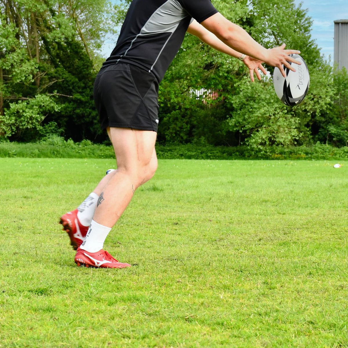Player stretching to throw the Precision Momentum Rugby Training Ball, shown from the side