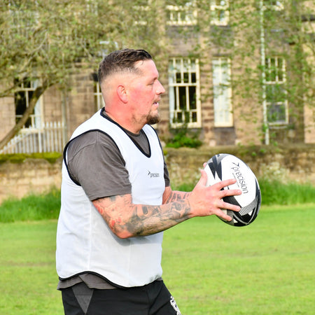Player in a white bib about to pass the Precision Momentum Rugby Training Ball in training