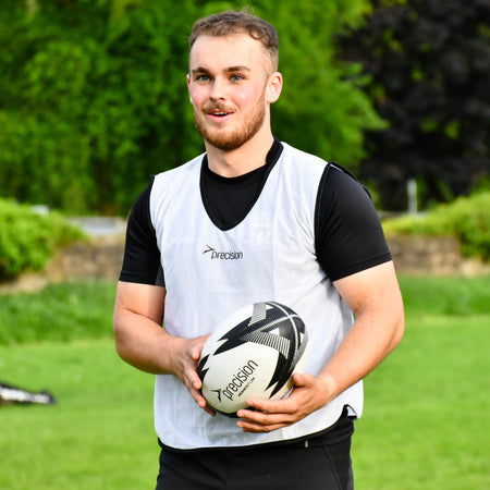 Smiling player in a white bib holding the grey Precision Momentum Rugby Training Ball