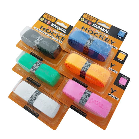 Six packs of Karakal XL PU Super Hockey Grip by Karakal, in black, blue, green, orange, white, and pink colors, are displayed in two rows on their distinctive orange and yellow retail packaging. Each cushioned PU Super grip delivers excellent comfort and control for your hockey stick.