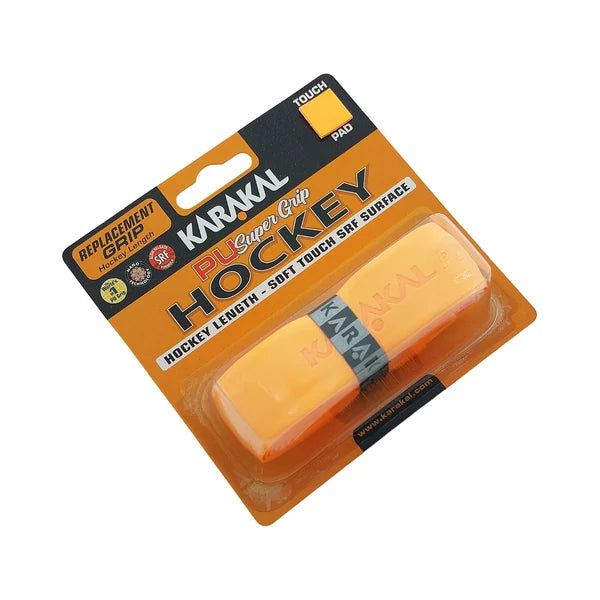 The Karakal XL PU Super Hockey Grip, in orange, is packaged in a plastic blister pack featuring black and orange branding. The packaging highlights product features such as its cushioned PU grip, with the word “HOCKEY” prominently displayed.