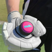 A person wearing a white padded glove holds the nub Sports ‘nub - Pink Six’ cricket ball, featuring pink and black colors with blue "nub." branding. Grass and part of the uniform are visible in the background.