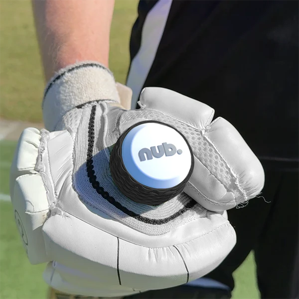 A person wearing white cricket gloves holds a nub Sports nub - White cricket bat handle attachment in their palm while standing on a sports field.