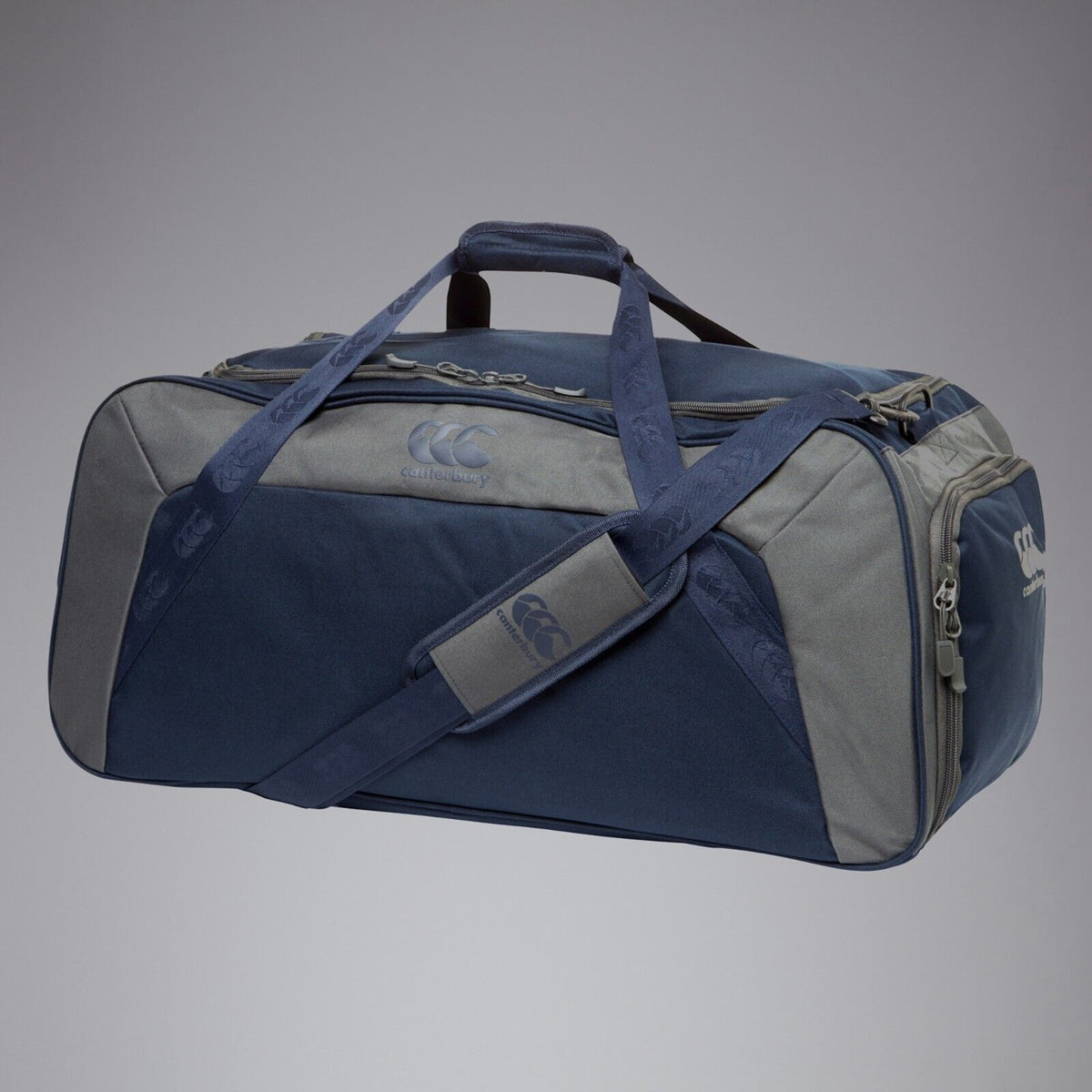 The Canterbury Classic Holdall Bag by Canterbury is a large, rectangular navy waterproof gym bag with padded handles, an adjustable shoulder strap, side pockets, zip closure, and the Canterbury logo on the front and side.