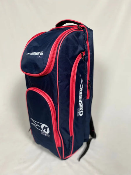 The Katchet KoachSak One2One bag in navy and pink, featuring the brand logo on the side and top, stands upright against a plain light background—ideal for carrying cricket equipment or one-to-one coaching sessions.