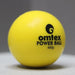 A bright yellow Omtex PowerBall weighted cricket ball with black "Omtex POWER BALL 400g" text is placed on a smooth, light surface, perfect for cricket training and improving batting power.