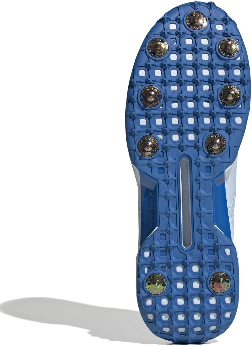 The image features the Adidas 22YDS White/Red/Royal Cricket Spikes 2026 with a blue sole, seven metallic spikes, and patterned tread for enhanced grip on grass.