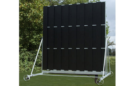 The Martin Berrill Sports Twenty/20 Sight Screen is a large, freestanding black screen with vertical panels and a high-visibility backdrop, mounted on a white metal frame, shown outdoors with grass and trees in the background.