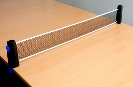 A close-up of a Sure Shot Matthew Syed Flex Net table tennis net by Sure Shot, attached to the edges of a light wooden table, with no paddles or ball visible.