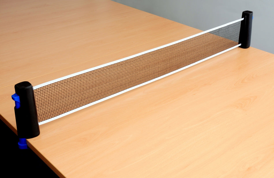 A close-up of a Sure Shot Matthew Syed Flex Net table tennis net by Sure Shot, attached to the edges of a light wooden table, with no paddles or ball visible.