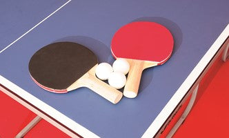 Two Butterfly Starter paddles (red and black) and three white ping pong balls are placed on the blue Butterfly Starter Table Tennis Table.