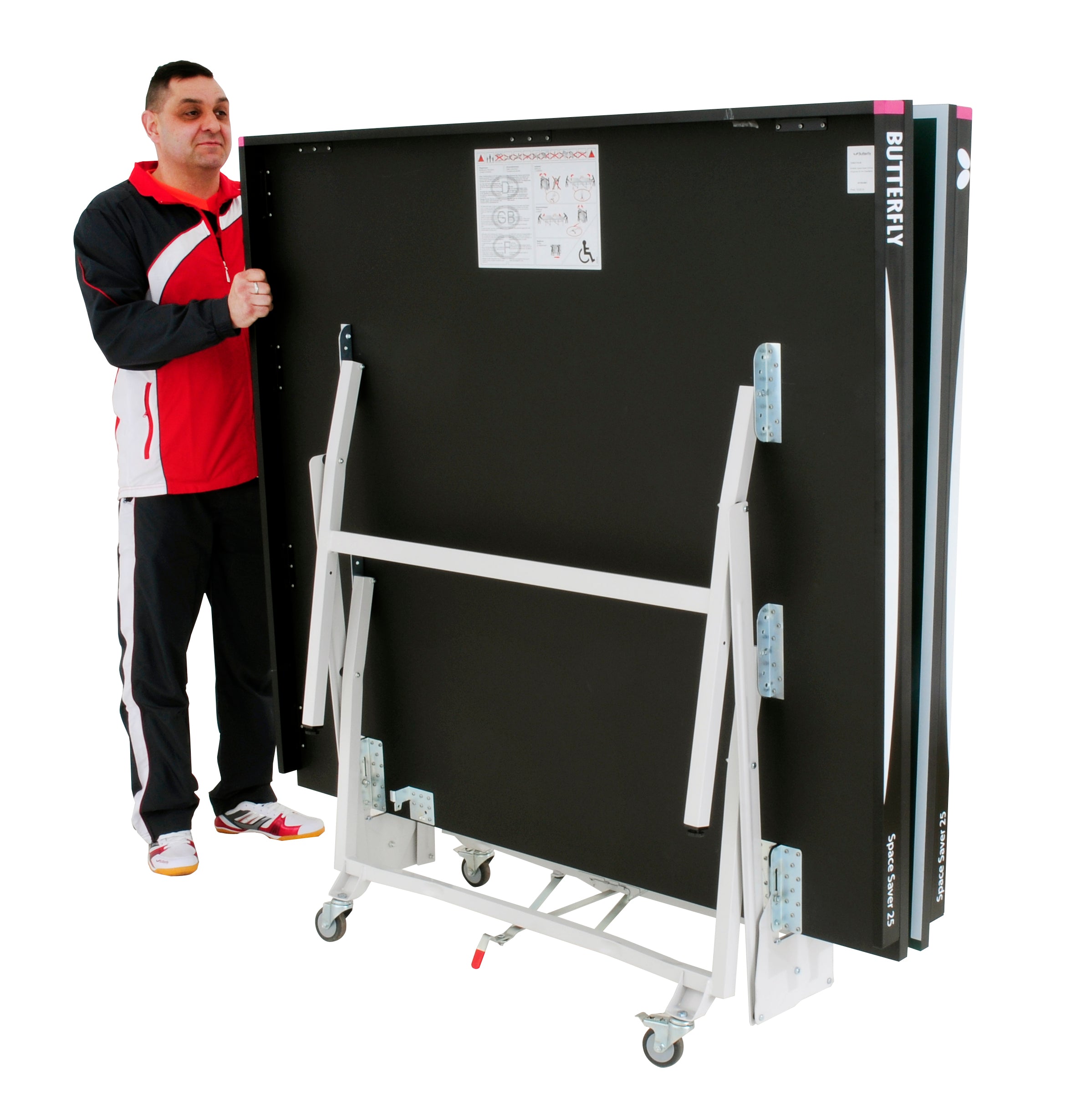 A man in sportswear stands beside a folded Butterfly Space Saver 22 Rollaway Table Tennis Table by Butterfly, showcasing its wheelchair-friendly design and compact storage on wheels.