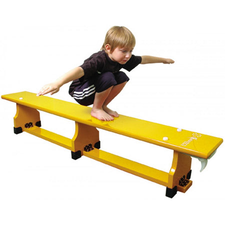 A young boy in athletic clothes balances with arms outstretched on a Sure Shot Coloured Balance Bench (11ft) by Sure Shot, demonstrating focus and stability.
