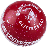 The Kookaburra Glitter ball is a red cricket training ball with white stitching, covered in glitter, featuring the brand name Kookaburra, a kookaburra bird logo, and the text "GLITTERBALL" printed on it.