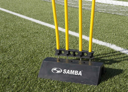 A black and yellow pole on Astro turf is supported by the Samba Sports Samba Rubber Mannequin Base, creating a striking contrast with the green field.