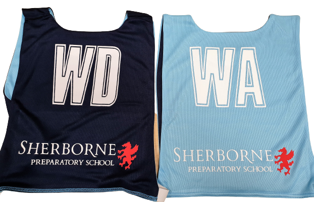 Two Personalised Gilbert Netball Bibs (Single Bibs), one WD in dark blue and one WA in light blue, both featuring Sherborne Preparatory School and a red lion logo printed at the bottom, by Gilbert.