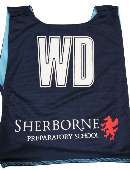 A navy blue Gilbert Personalised Netball Bib (Single) with large white WD on the back, and Sherborne Preparatory School plus a red lion logo printed at the bottom.