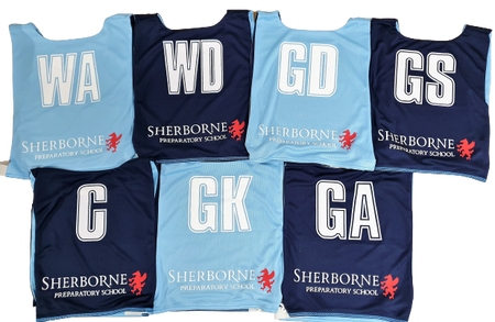 Seven Gilbert Personalised Netball Bibs (Single Bibs) in light blue and navy, each with a unique position (WA, WD, GD, GS, C, GK, GA), Sherborne Preparatory School name and red lion logo on every bib.